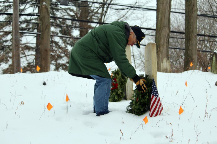 Navy veteran Ron Egut, of Norwalk, lays a wreath on the headstone of soldier buried at the cemetery near Comstock Lane and Signal Hill Road on Saturday, Dec. 17.